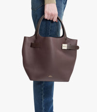 A.P.C. Daria Bag - Woman holding burgundy Daria bag wearing blue jeans.