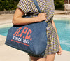 A.P.C. Denim - Woman in a dress with denim tote bag standing by pool.