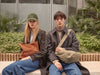 A.P.C.Winter Sale - Woman and man model wearing winter clothing sitting on a bench against a botantical background