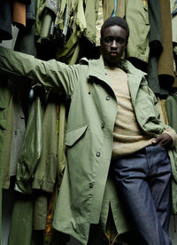 A.P.C. - Man wearing green parka with other green outerwear pieces behind him.