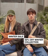 A.P.C.Winter Sale - Woman and man model wearing winter clothing sitting on a bench against a botantical background