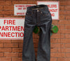 A.P.C. Denim - a pair of denim propped up on a sprinkler valve against a brick wall