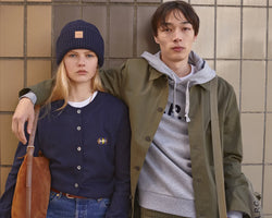 A.P.C. Fall/Winter Campaign - Man and woman leaning on a wall wearing collegiate clothing.