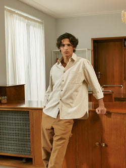 A.P.C. The Brand - man wearing an off-white shirt and beige pants standing in front of a credenza