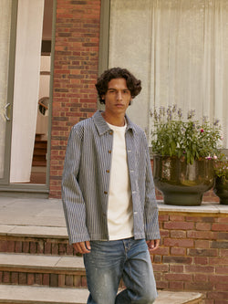 A.P.C. The Brand - man wearing striped jacket and jeans standing in front of house stairs.