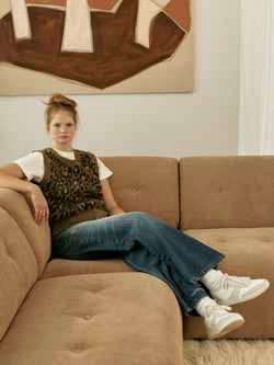 A.P.C. The Brand - woman wearing leopard sweater vest and jeans sitting on a couch.