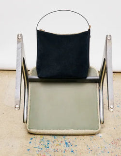 A.P.C. Fall/Winter Campaign - Black suede Vera bag sitting on the top of a flipped over chair.