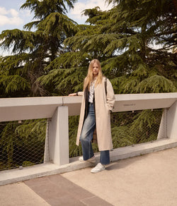 A.P.C. Fall/Winter Campaign - Woman standing on bridge wearing coat and blue jeans.